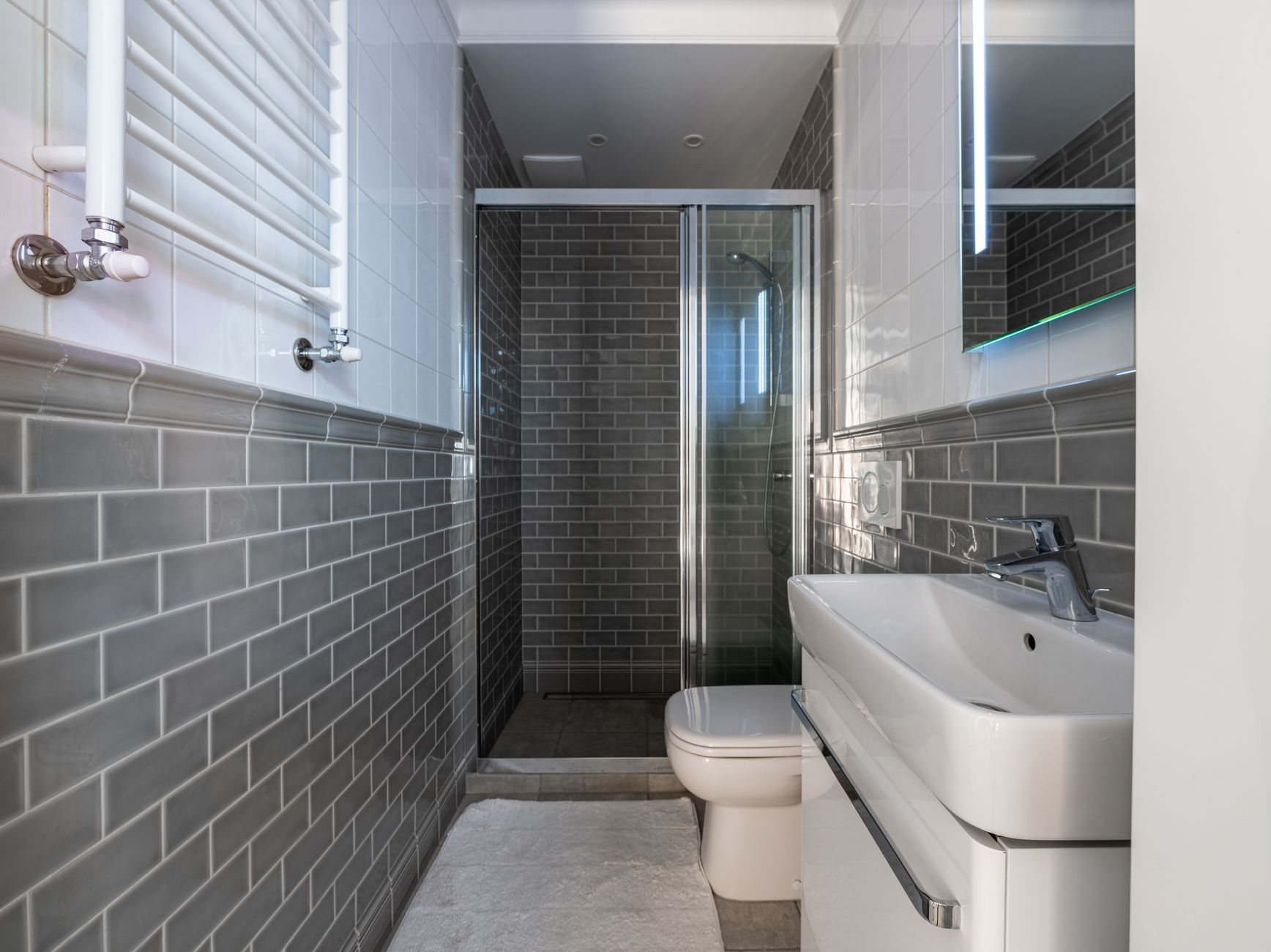 Compact bathroom with gray subway tile and a glass-enclosed shower