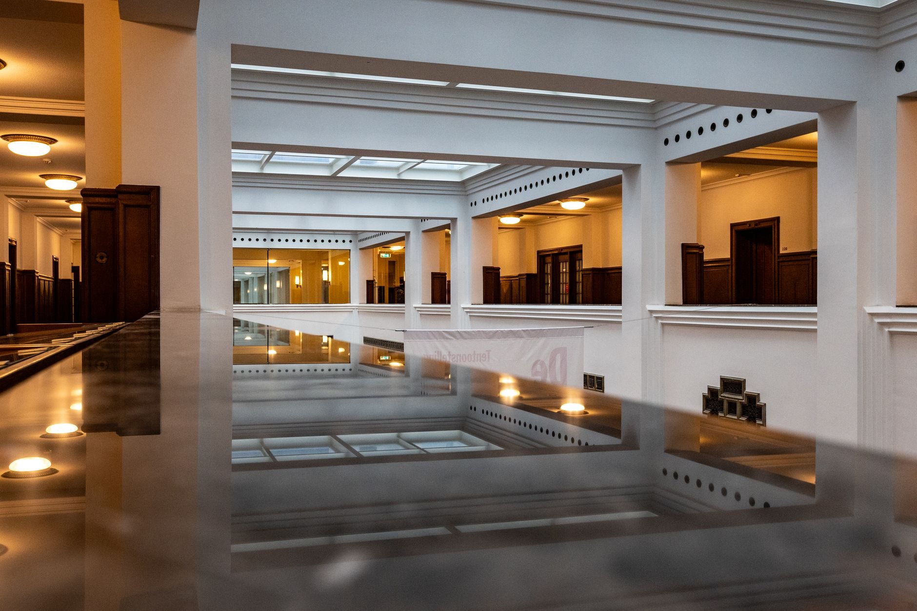 Commercial interior spacious modern atrium with skylight ceiling and reflective surfaces, featuring warm lighting