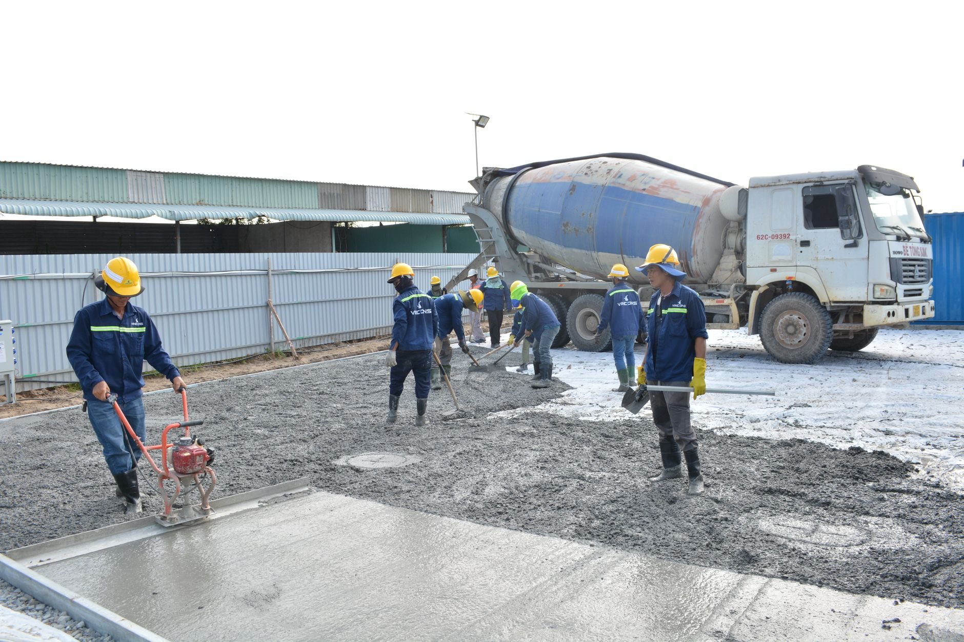 Concrete crew pouring from a mixer truck and leveling a structural placement on a Utah job site