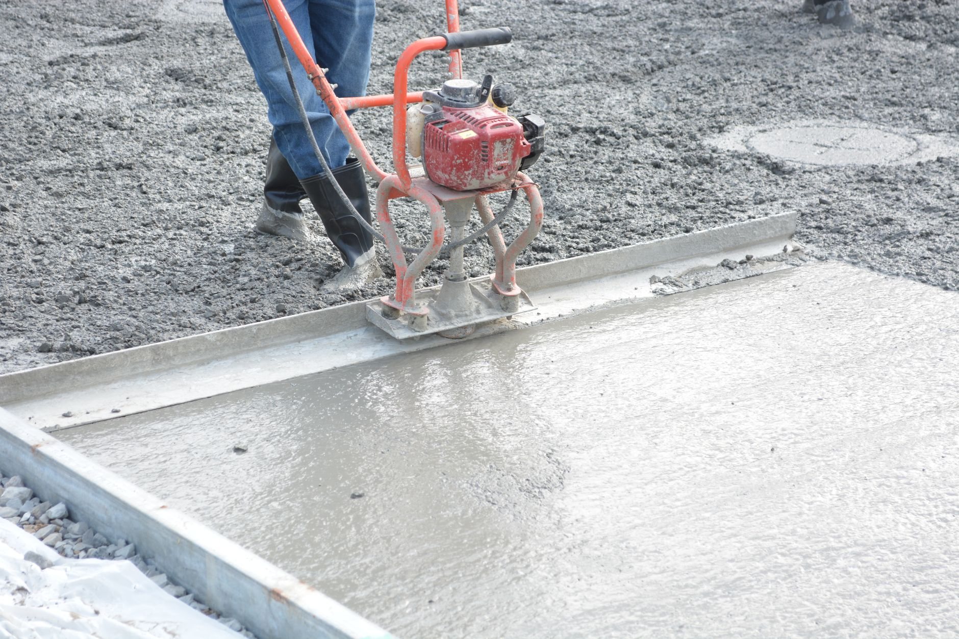 Construction worker power-troweling freshly poured air-entrained concrete flatwork
