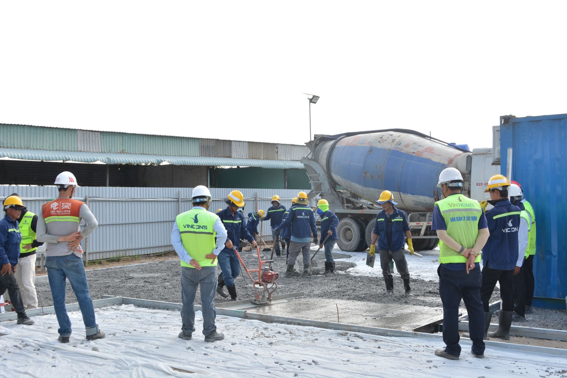 Concrete crew in helmets and vests working with a cement mixer truck on a commercial construction site