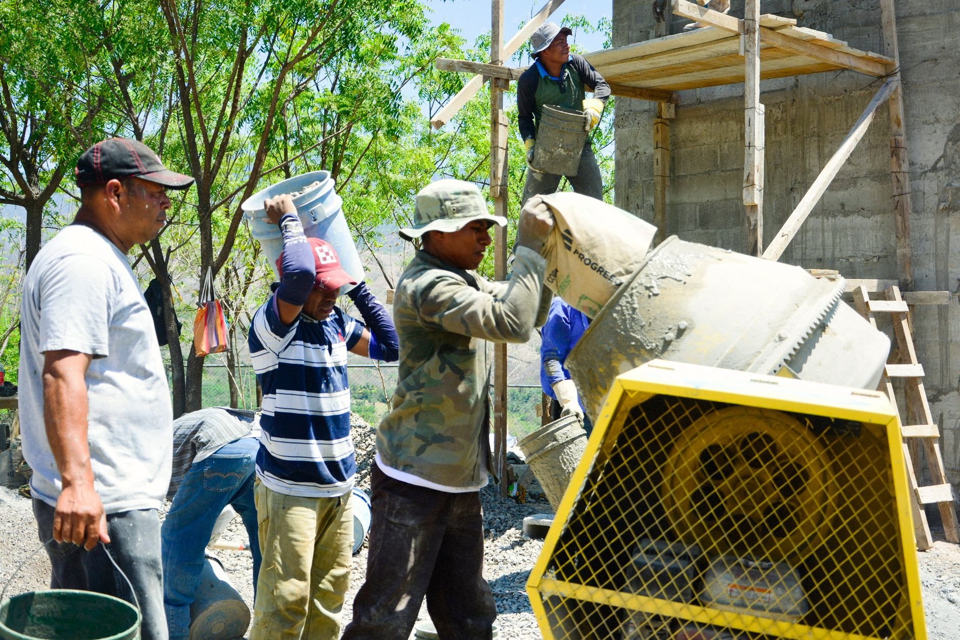 Crew placing concrete from mixers into formed structural elements on an outdoor site