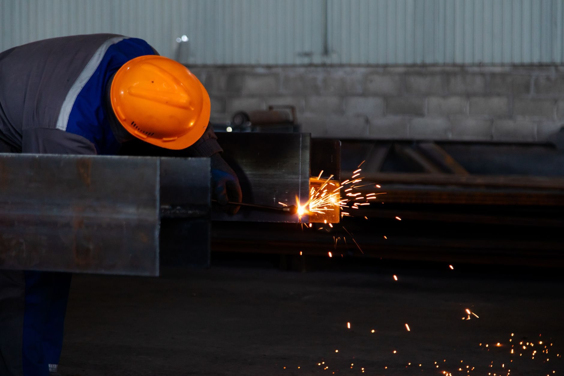 Welder in protective gear field welding a steel beam connection