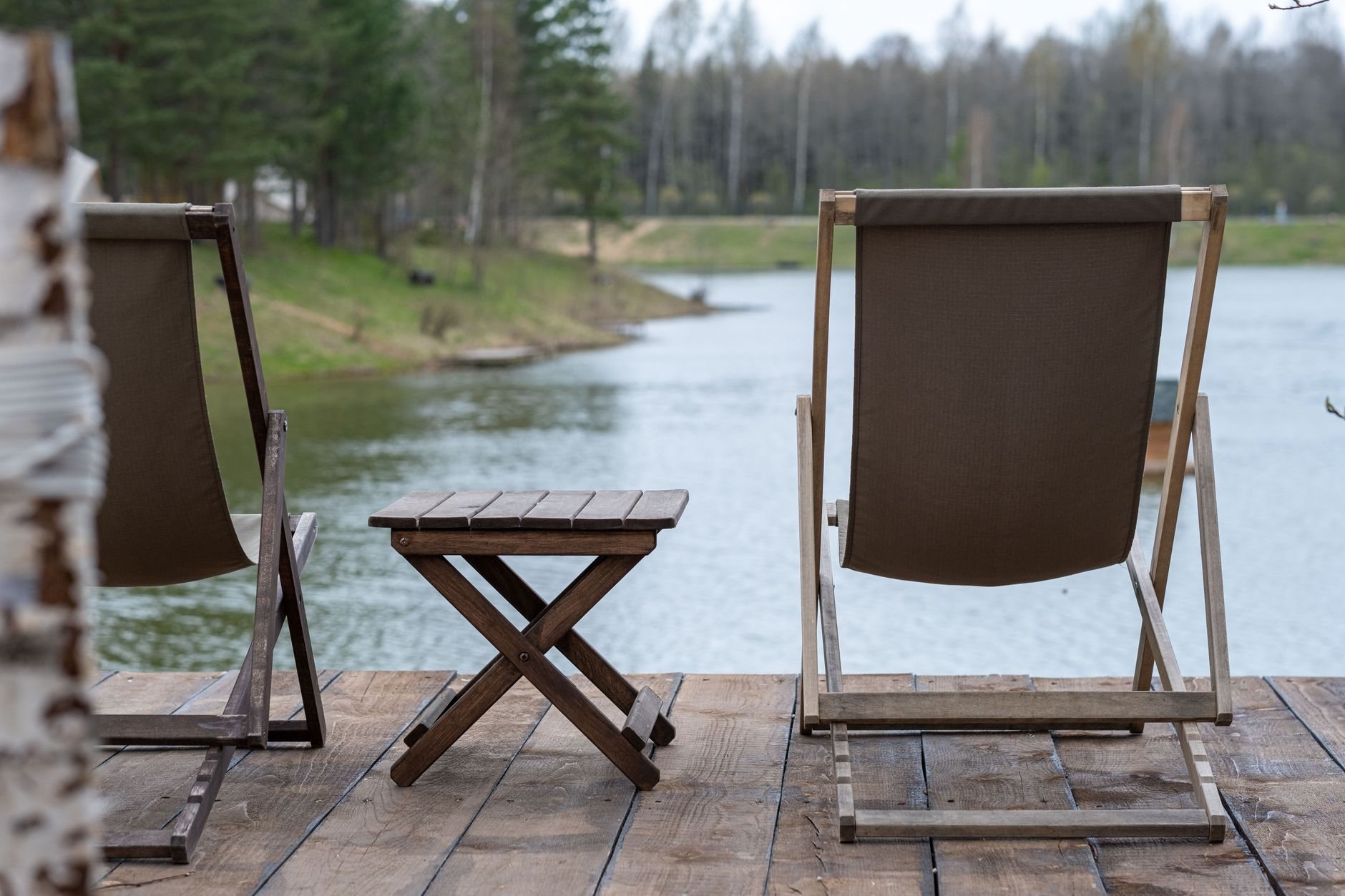 Wooden deck chairs and table on a cabin deck overlooking a mountain lake