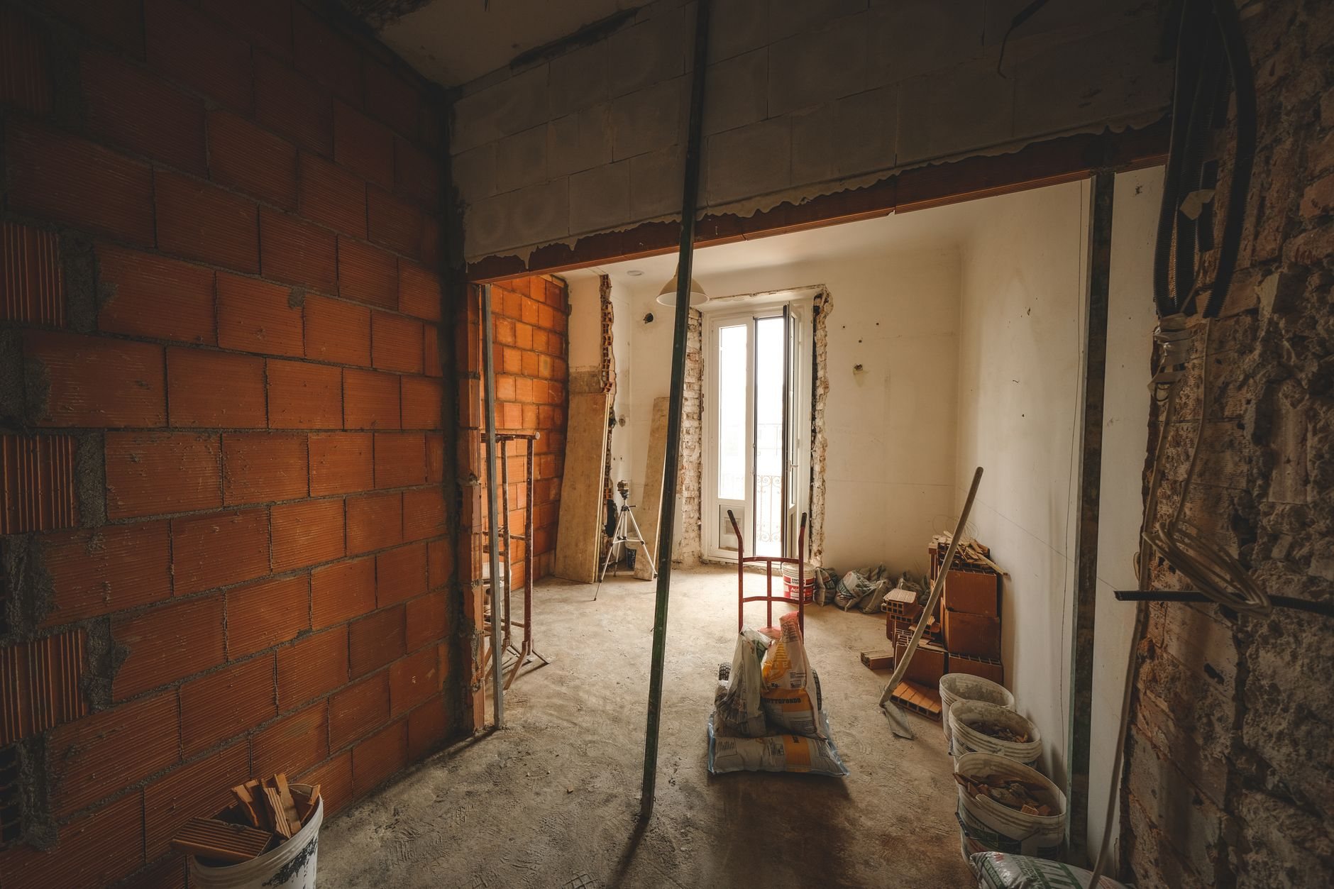 Selective demolition in progress: a room stripped to exposed brick walls with construction materials staged on site