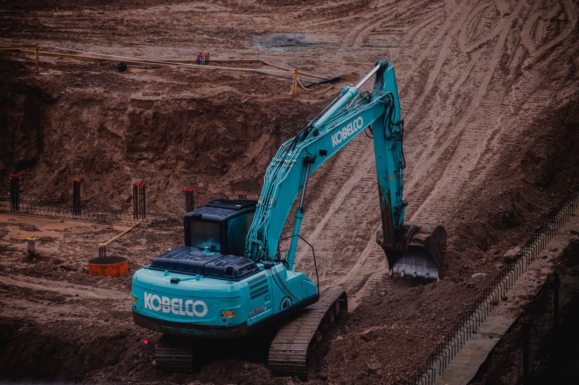 Excavator opening a trench along a foundation for exterior waterproofing and drain installation