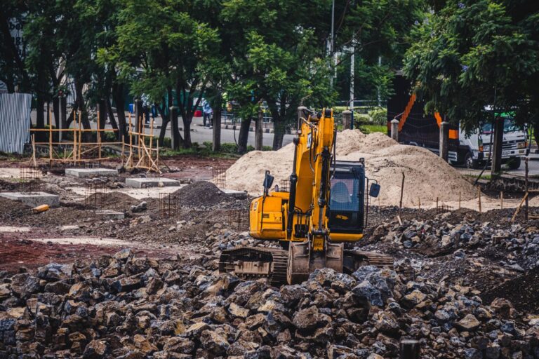 Excavation: a yellow excavator working at an urban construction site surrounded by rocks and trees