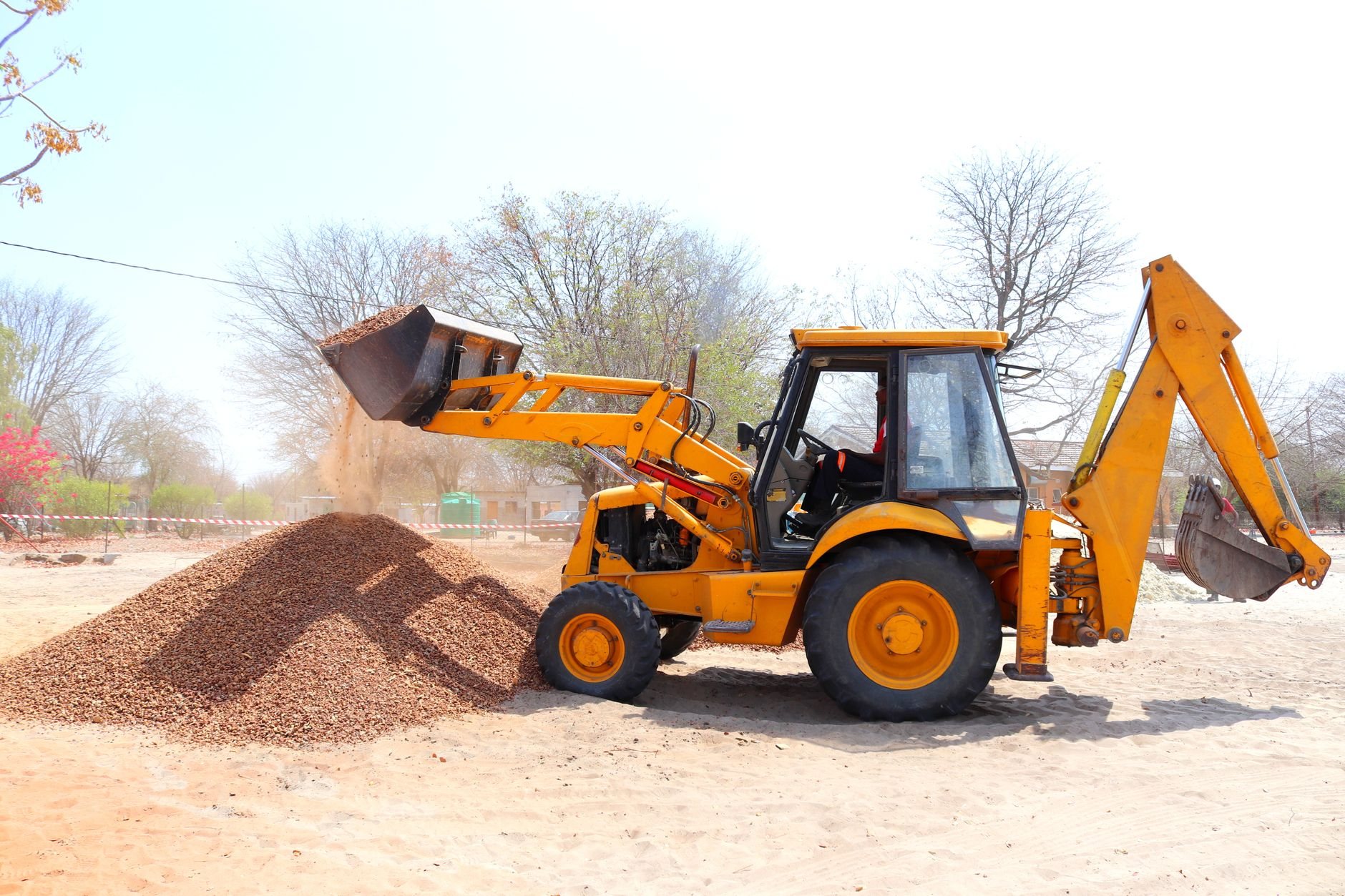 Excavator moving gravel fill at an outdoor construction site