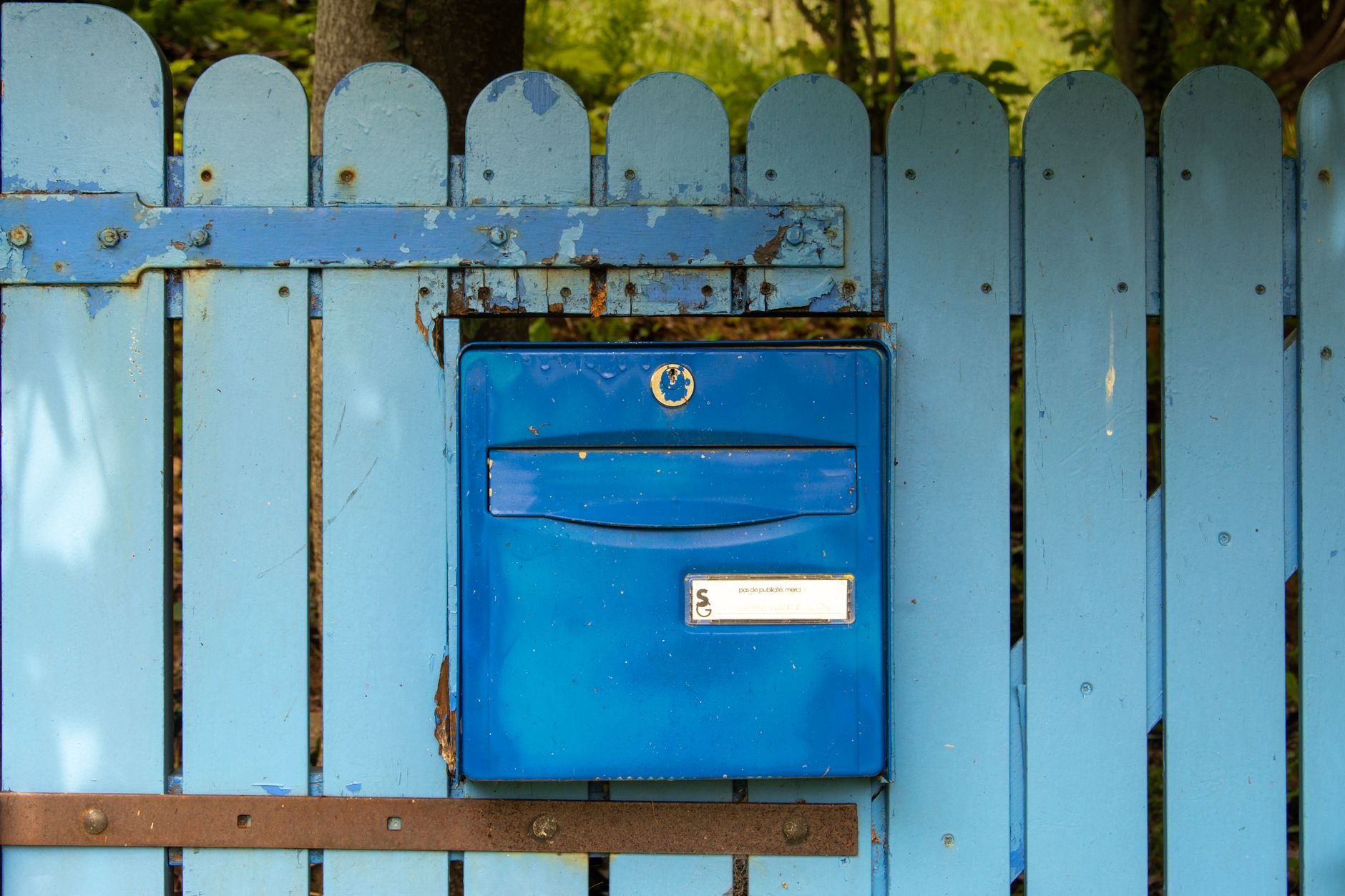 Weathered blue wood fence with aged pickets — the kind of wear that fence repair or replacement addresses