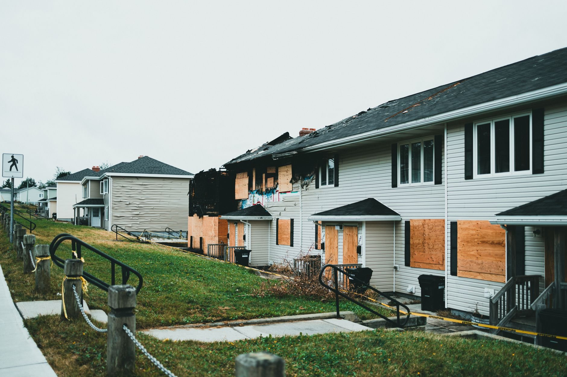 Boarded-up suburban homes with visible fire damage awaiting reconstruction