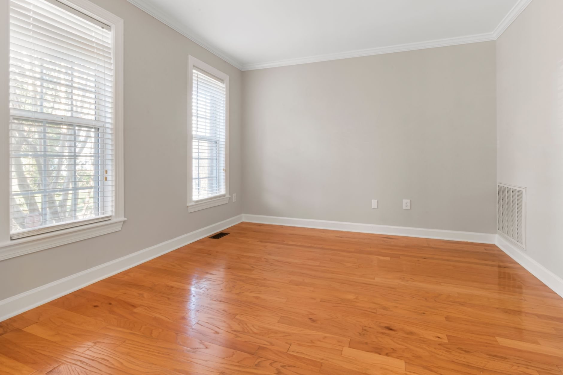 Freshly floored room with neutral walls, ready for baseboard and window trim installation