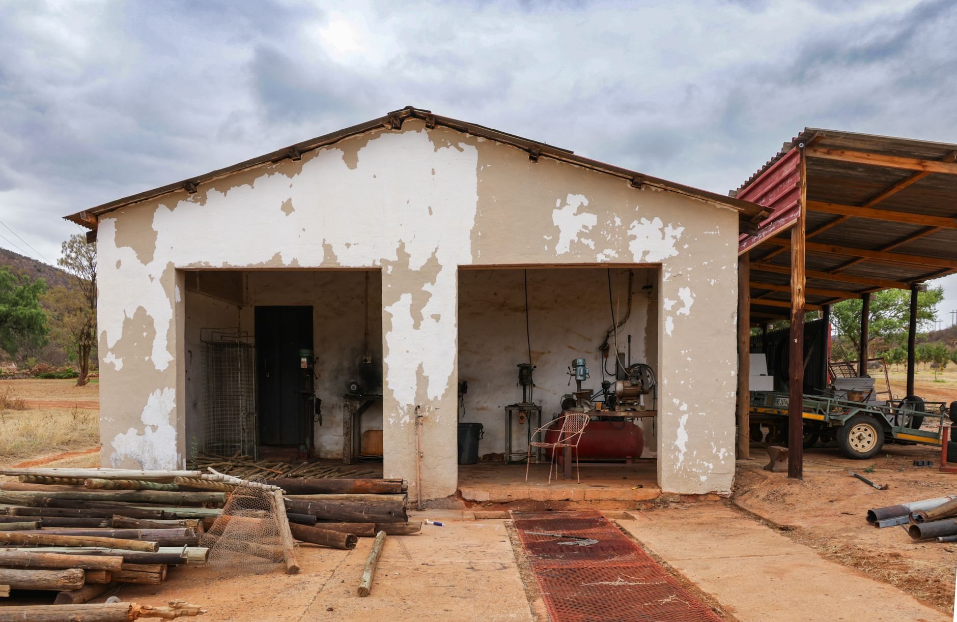 Garage and shop a rustic farm building with vintage equipment, surrounded by open land and a cloudy sky