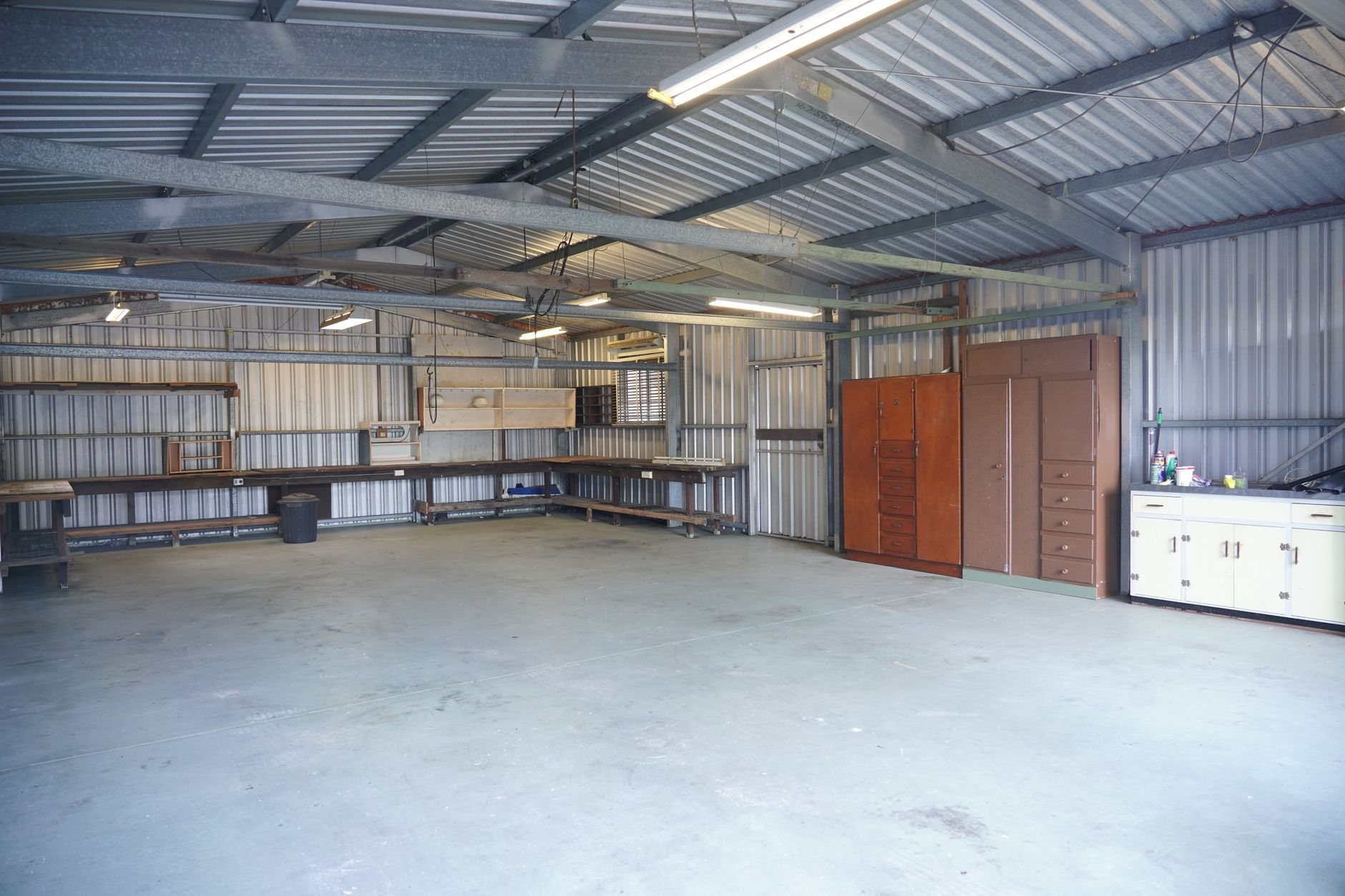 Interior of a newly built detached shop with steel walls, storage cabinets, and workbenches