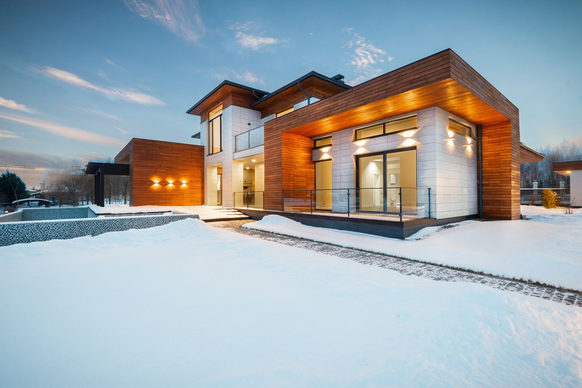 Custom home with stone and wood facade overlooking a snowy large lot