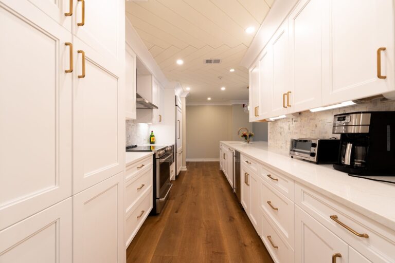 Remodeled kitchen with bright modern kitchen with white cabinets, wooden floor, and appliances