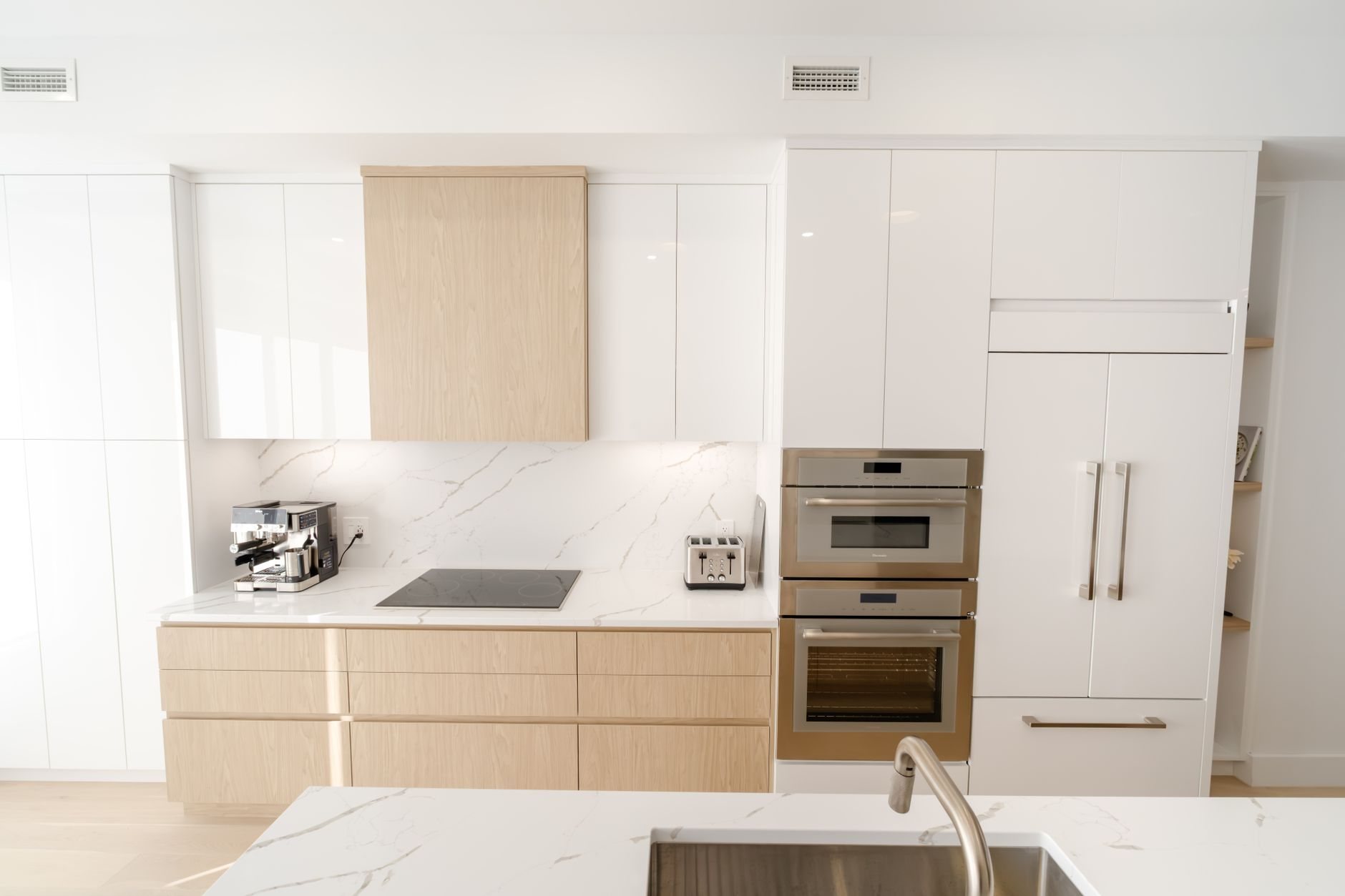 Sleek kitchen with built-in appliances and marble countertops representative of a hand-selected luxury finish package