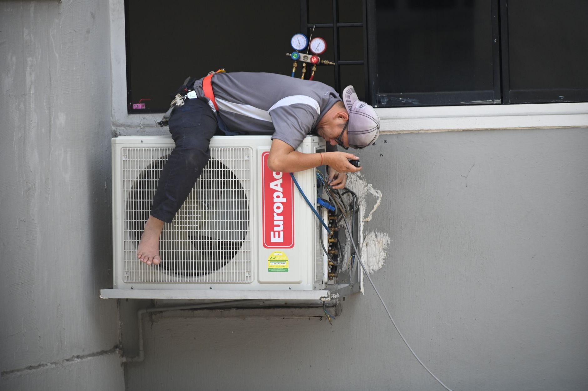 Technician servicing a wall-mounted air conditioning unit during a building systems project
