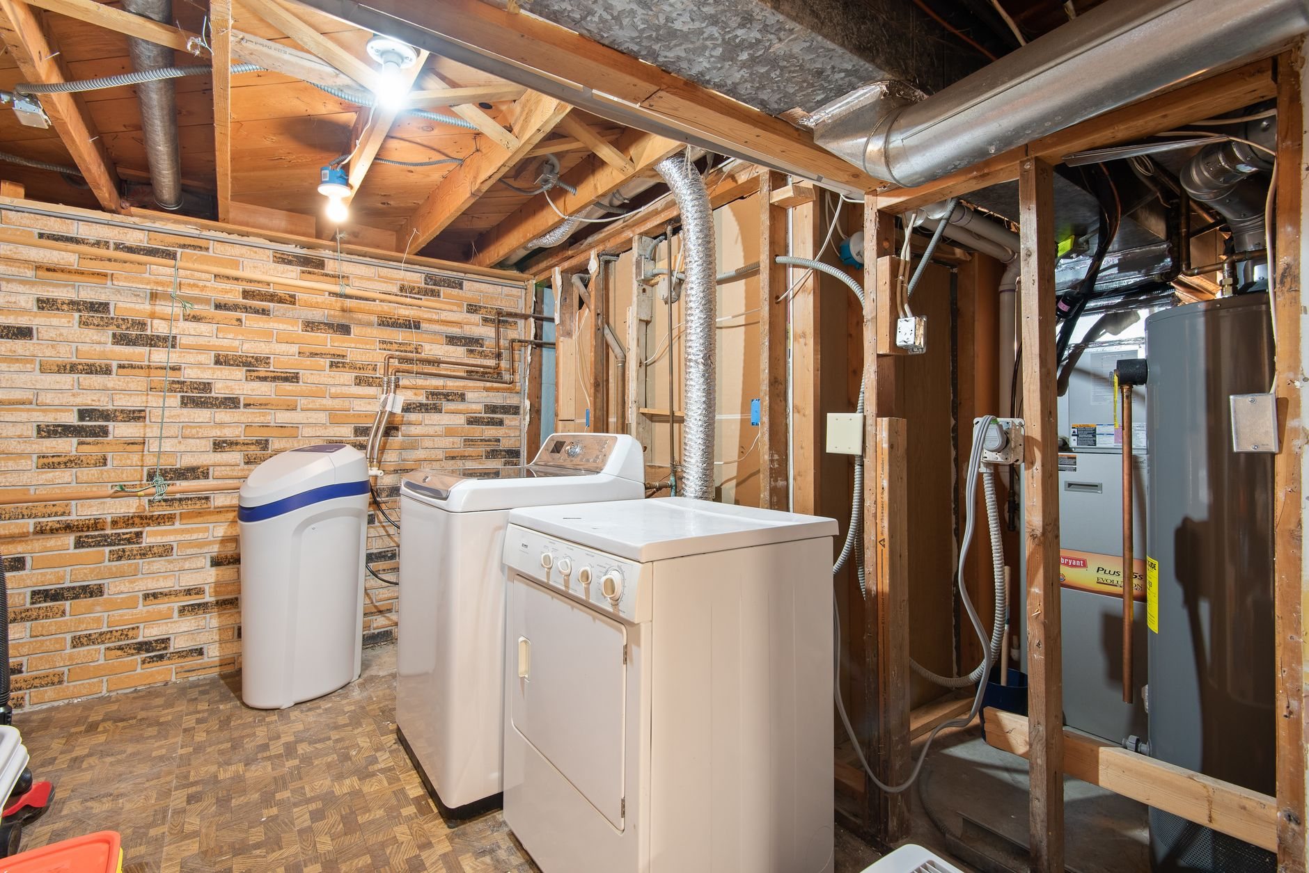 Basement mechanical and laundry area with plumbing and systems exposed before finishing