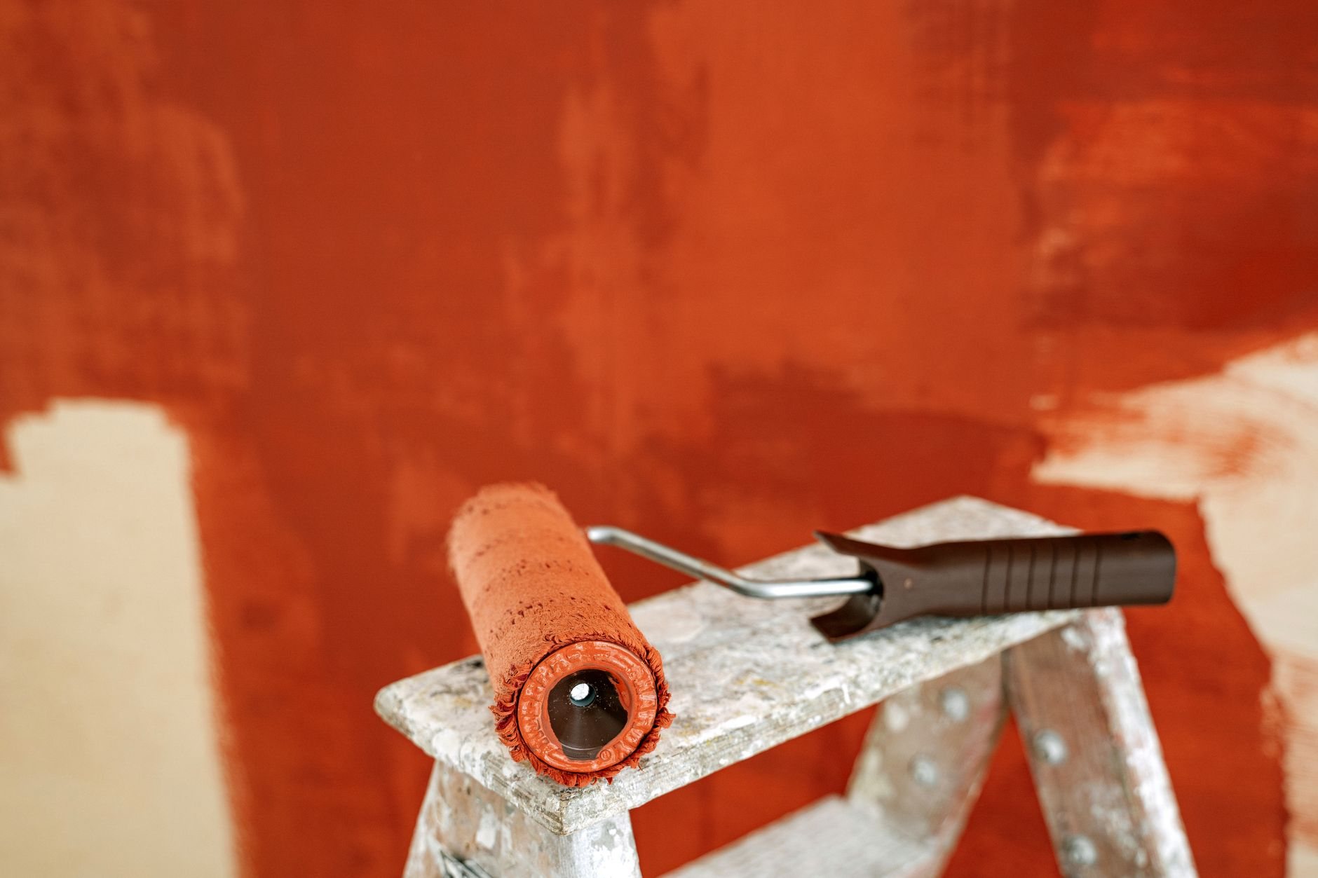 Paint roller resting on a stepladder against a freshly finished drywall wall during a Utah renovation