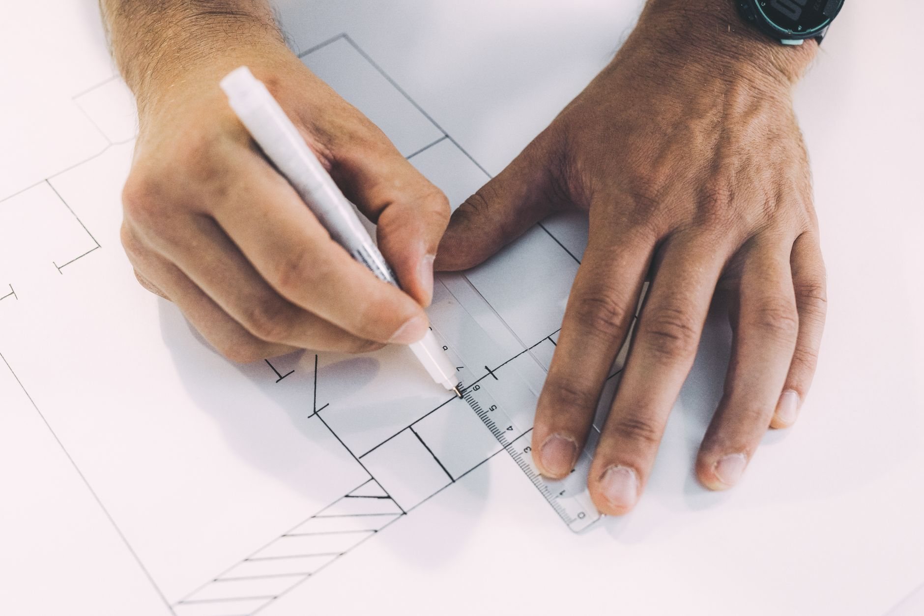 Consultant marking up architectural plans with ruler and pen during a code review