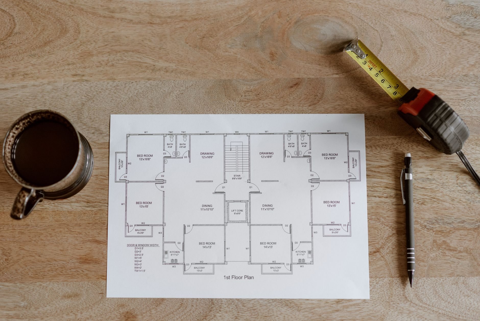 Plan set, tape measure, and notes laid out on a table during a construction advisory review