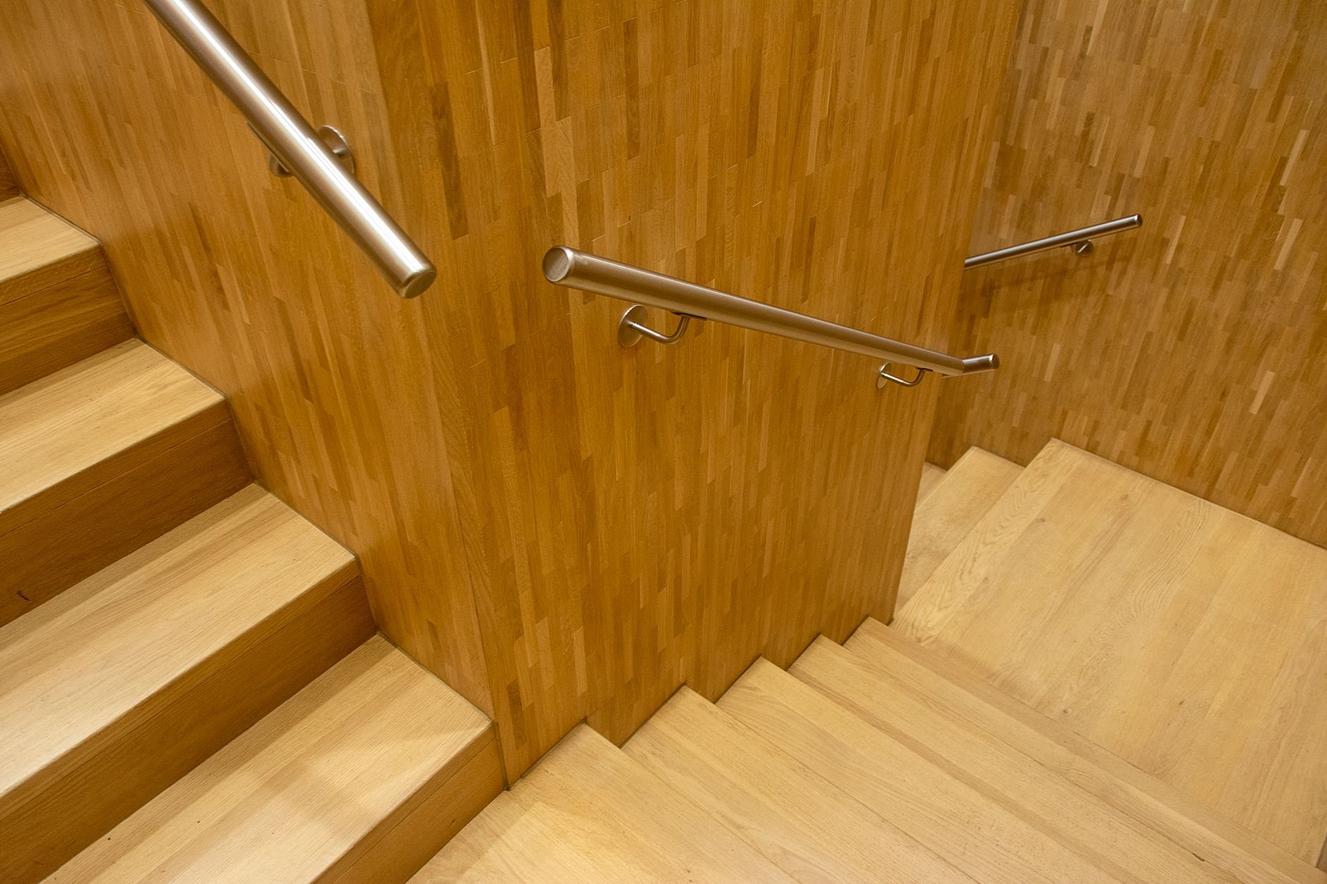 Wooden staircase with metal handrail providing code-compliant access to an upper floor