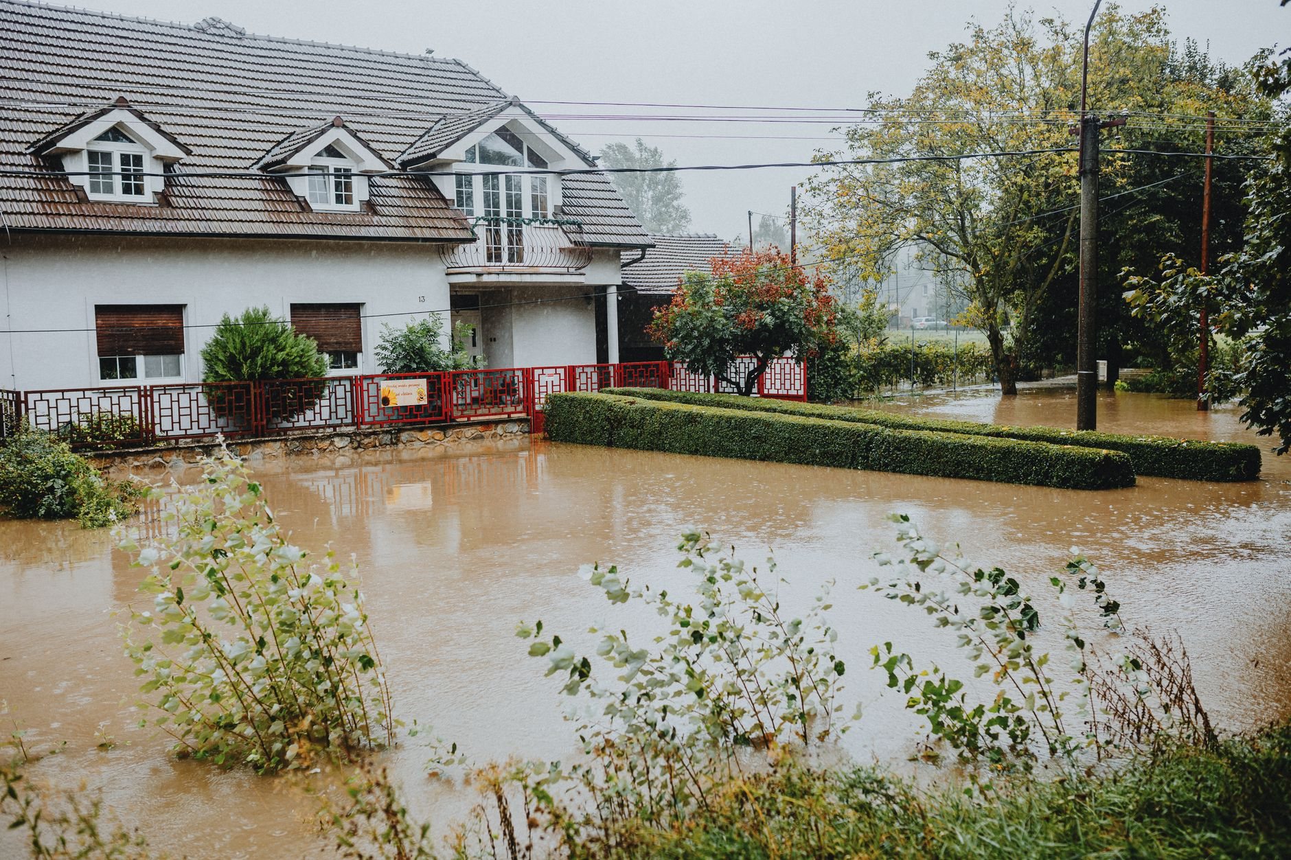Suburban house surrounded by floodwater after heavy rain, before emergency stabilization