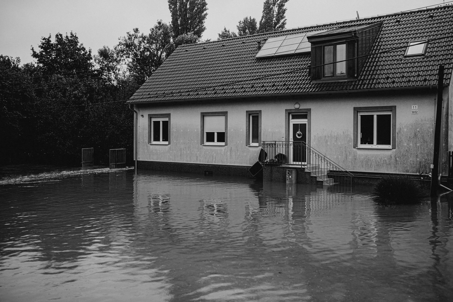 Suburban house surrounded by floodwater, the outcome an unfastened roof tarp invites