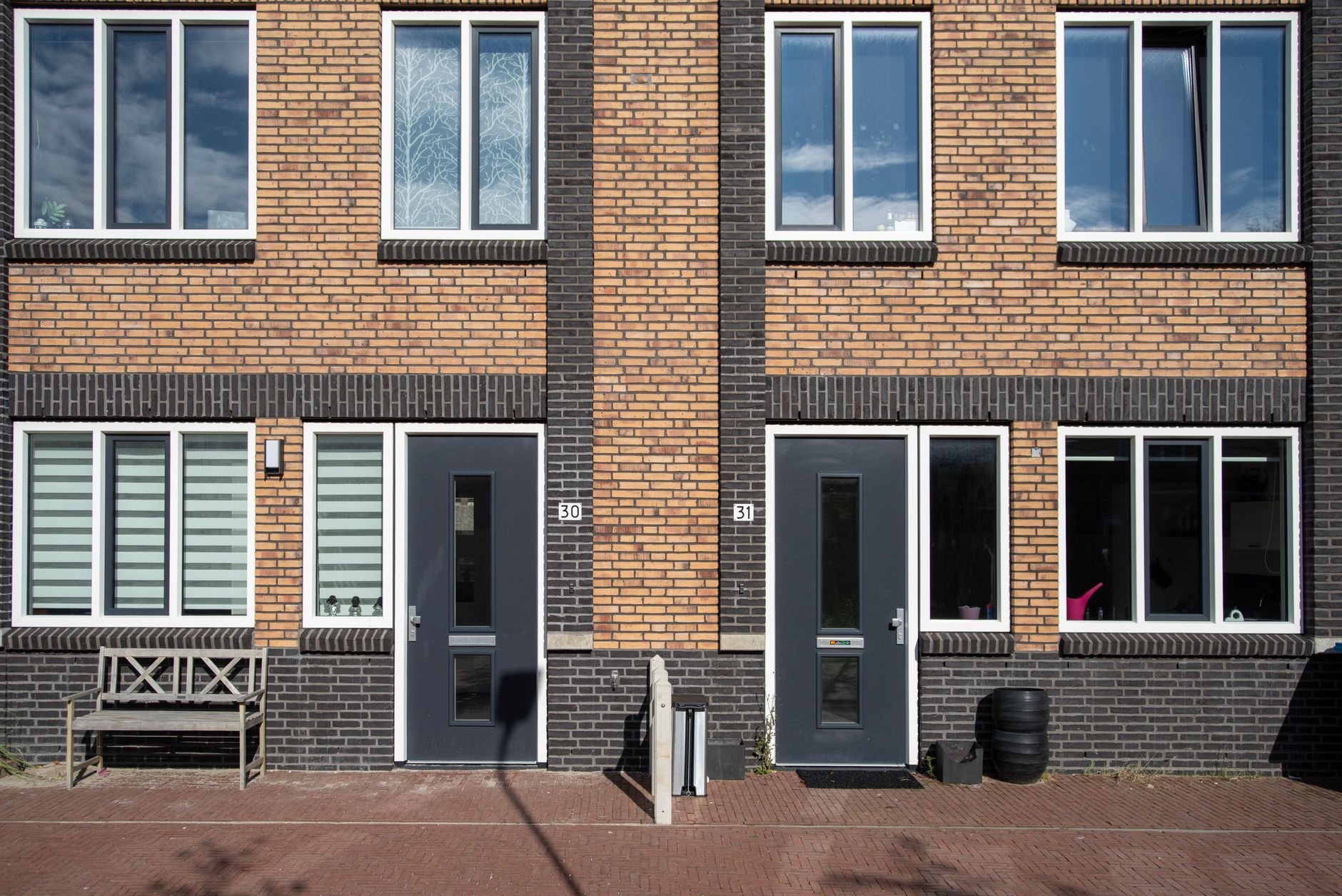 Modern brick home exterior with large newly installed windows and contrasting entry doors
